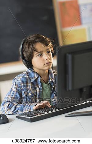 Stock Photo - Schoolboy (6-7) using computer in classroom. Fotosearch