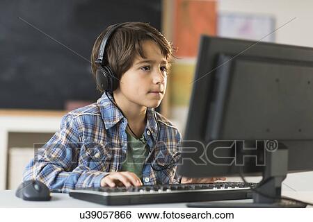 Stock Photograph - Schoolboy (6-7) using computer in classroom. Fotosearch