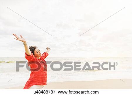 Side view of woman standing with arms up on beach View Large Photo Image Stock Photo - Side view of woman standing with arms up on beach. Fotosearch