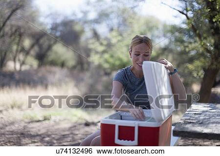 Smiling woman opening cooler in park View Large Photo Image Stock Photograph - Smiling woman opening cooler in park. Fotosearch