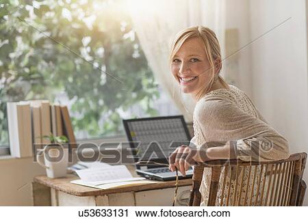 Smiling woman sitting at desk and looking over shoulder View Large Photo Image Stock Image - Smiling woman sitting at desk and looking over shoulder . Fotosearch