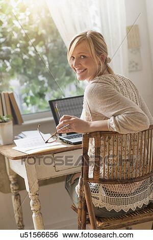 Stock Photograph - Smiling woman sitting at desk and looking over shoulder . Fotosearch