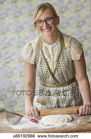 Smiling woman using rolling pin while kneading dough View Large Photo Image Stock Photo - Smiling woman using rolling pin while kneading dough. Fotosearch