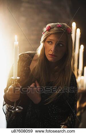 Stock Photo - Sorceress holding candle in dark room. Fotosearch
