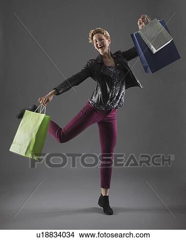 Studio shot of cheerful woman holding shopping bags View Large Photo Image Picture - Studio shot of cheerful woman holding shopping bags. Fotosearch