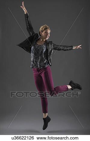 Studio shot of cheerful woman jumping with arms raised View Large Photo Image Stock Photograph - Studio shot of cheerful woman jumping with arms raised. Fotosearch