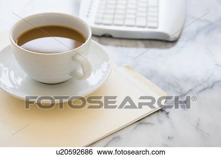 Stock Photograph - Studio shot of coffee cup, computer keyboard and files. Fotosearch