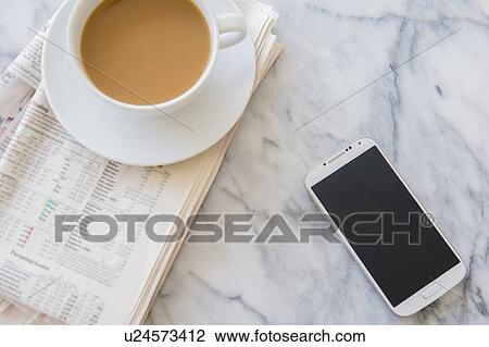 Stock Image - Studio shot of coffee cup, newspaper and smart phone. Fotosearch