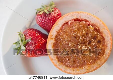 Stock Image - Studio shot of grapefruit with caramelized sugar and strawberries. Fotosearch