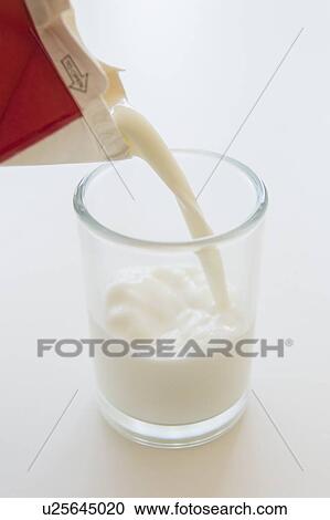Stock Image - Studio shot of milk pouring into glass. Fotosearch