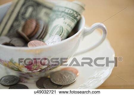 Stock Image - Studio shot of money in tea cup. Fotosearch