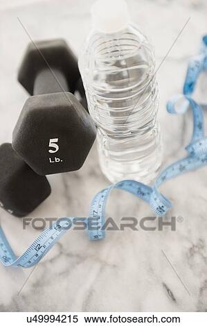 Stock Photography - Studio shot of water bottle, measuring tape and weights. Fotosearch