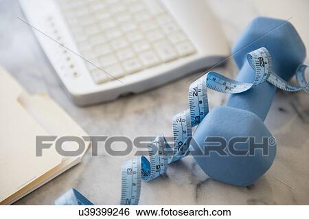 Stock Photograph - Studio shot of weight, measuring tape, files and computer keyboard. Fotosearch