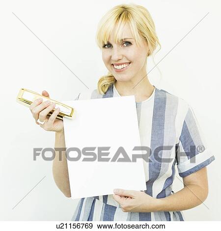 Stock Photo - Studio shot of woman holding blank paper and stapler. Fotosearch