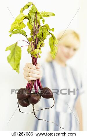 Stock Photograph - Studio shot of woman holding bunch of beetroots. Fotosearch