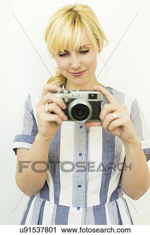 Stock Image - Studio shot of woman holding camera. Fotosearch