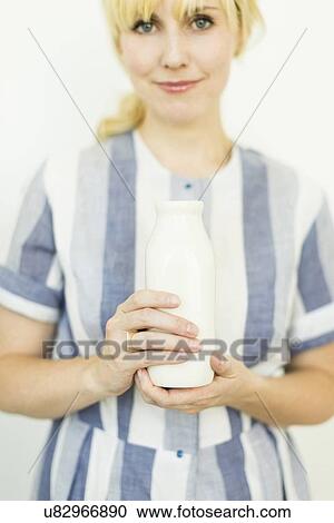 Stock Image - Studio shot of woman holding milk bottle. Fotosearch