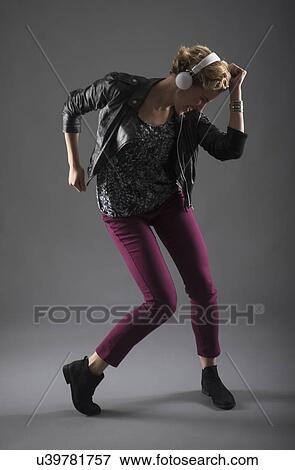 Stock Photo - Studio shot of woman listening to music and dancing. Fotosearch