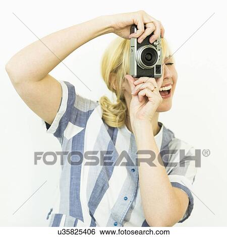 Stock Photograph - Studio shot of woman photographing with camera. Fotosearch