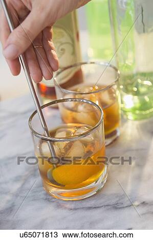 Stock Image - Studio shot of woman's hand stirring drink. Fotosearch