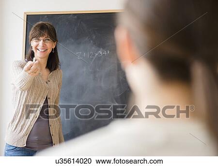 Teacher encouraging teenage student (14-15) to come to blackboard View Large Photo Image Stock Image - Teacher encouraging teenage student (14-15) to come to blackboard. Fotosearch