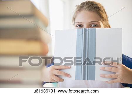 Teenage girl (12-13) hiding face behind book View Large Photo Image Stock Image - Teenage girl (12-13) hiding face behind book. Fotosearch