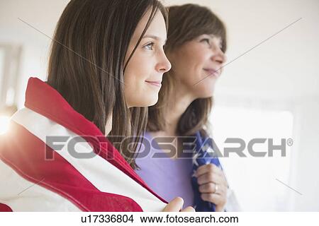 Picture - Teenage girl (14-15) and her mom wrapped in American Flag on Fourth of July. Fotosearch