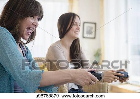 Teenage girl (14-15) playing video games with her mom View Large Photo Image Stock Photo - Teenage girl (14-15) playing video games with her mom. Fotosearch