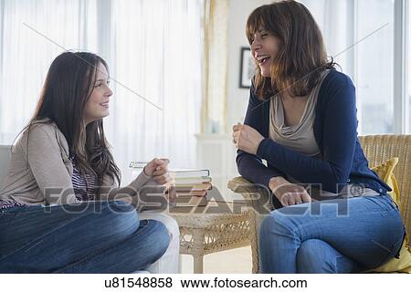 Stock Photo - Teenage girl (14-15) talking with her mom in living room. Fotosearch