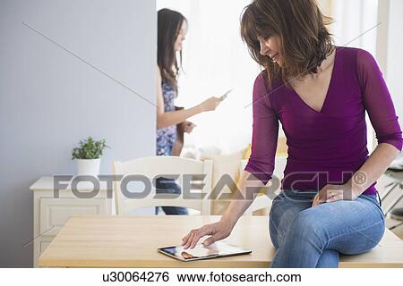 Teenage girl (14-15) texting and mom using digital tablet in living room View Large Photo Image Stock Photograph - Teenage girl (14-15) texting and mom using digital tablet in living room. Fotosearch