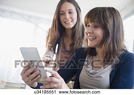 Teenage girl (14-15) using digital tablet with her mom in living room View Large Photo Image Stock Image - Teenage girl (14-15) using digital tablet with her mom in living room. Fotosearch