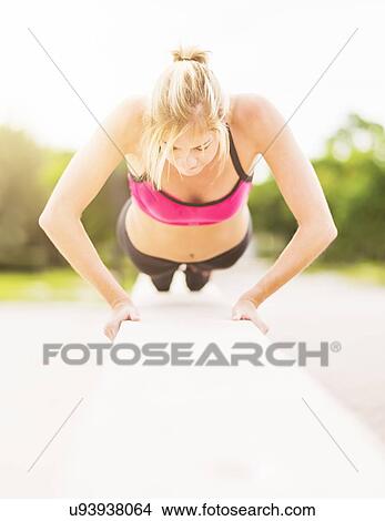 Picture - Woman doing pushups outdoors. Fotosearch