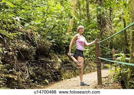 Stock Photo - Woman in forest, stretching leg. Fotosearch
