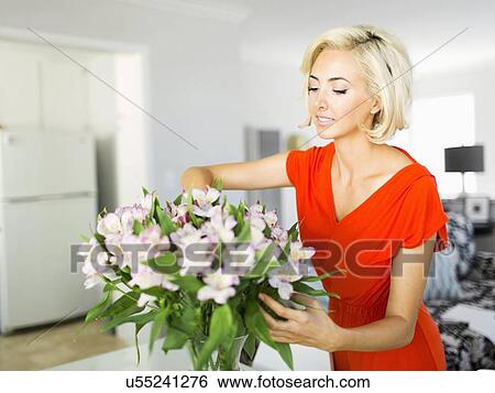 Stock Photograph - Woman in living room with bunch of flowers. Fotosearch