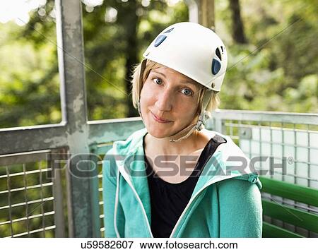 Stock Photo - Woman in protective helmet and sitting at net elevator looking at camera. Fotosearch