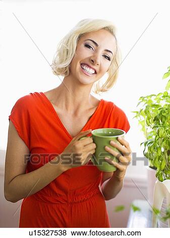 Stock Photo - Woman in red dress holding green mug. Fotosearch