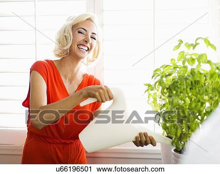 Woman in red dress watering potted plant View Large Photo Image Stock Image - Woman in red dress watering potted plant. Fotosearch
