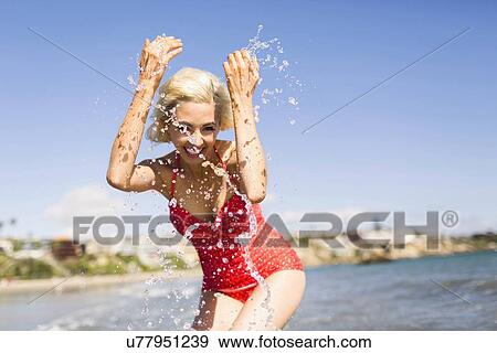 Woman in red swimming costume splashing water on beach View Large Photo Image Stock Photo - Woman in red swimming costume splashing water on beach. Fotosearch