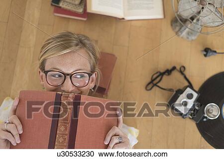 Stock Image - Woman lying down on floor and peeking. Fotosearch