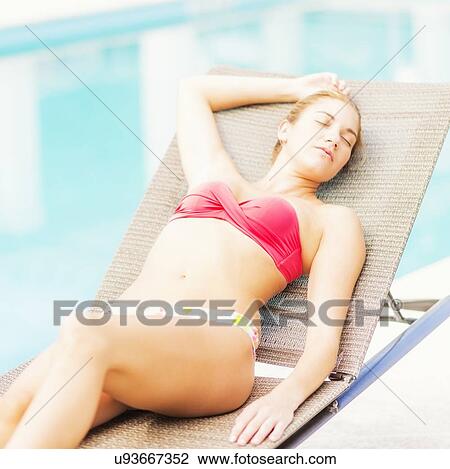 Stock Image - Woman lying on next to swimming pool. Fotosearch