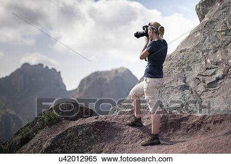 Stock Photography - Woman photographing in mountains. Fotosearch