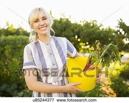 Woman picking vegetables in garden View Large Photo Image Stock Photo - Woman picking vegetables in garden. Fotosearch