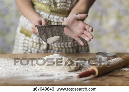 Woman sifting flour while kneading dough View Large Photo Image Stock Image - Woman sifting flour while kneading dough. Fotosearch