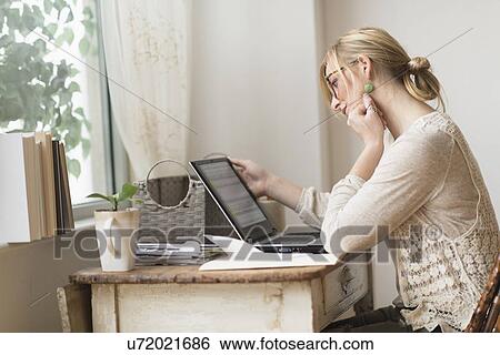 Stock Photograph - Woman sitting at desk and contemplating . Fotosearch