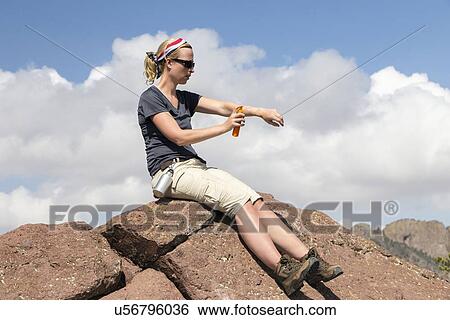 Woman sitting on rock and applying suntan lotion View Large Photo Image Stock Photograph - Woman sitting on rock and applying suntan lotion. Fotosearch
