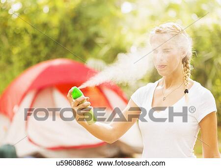 Stock Image - Woman spraying head with bug spray. Fotosearch