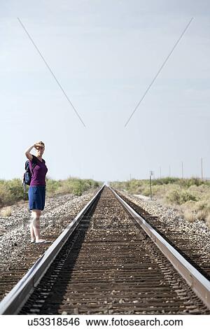 Woman standing by railroad track View Large Photo Image Stock Photograph - Woman standing by railroad track. Fotosearch