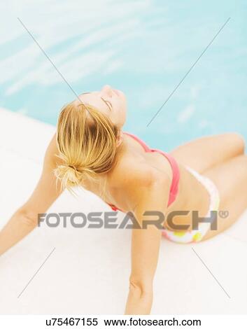 Woman sunbathing next to swimming pool View Large Photo Image Stock Photography - Woman sunbathing next to swimming pool. Fotosearch