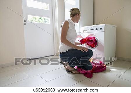 Stock Image - Woman taking laundry out of washing machine. Fotosearch