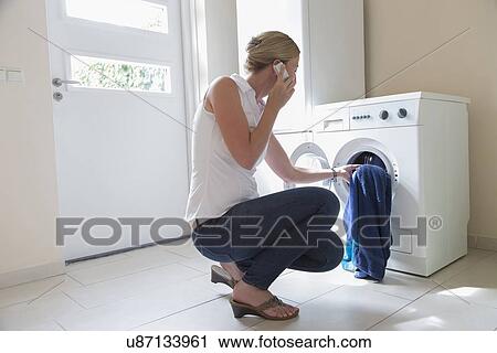 Woman taking laundry out of washing machine View Large Photo Image Stock Image - Woman taking laundry out of washing machine. Fotosearch